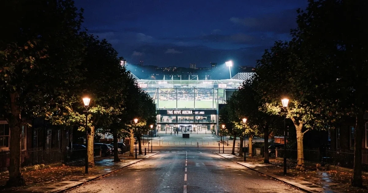 Ein hell erleuchtetes Stadion aus der Ferne bei Nacht, davor eine stille Straße und ein paar Bäume.