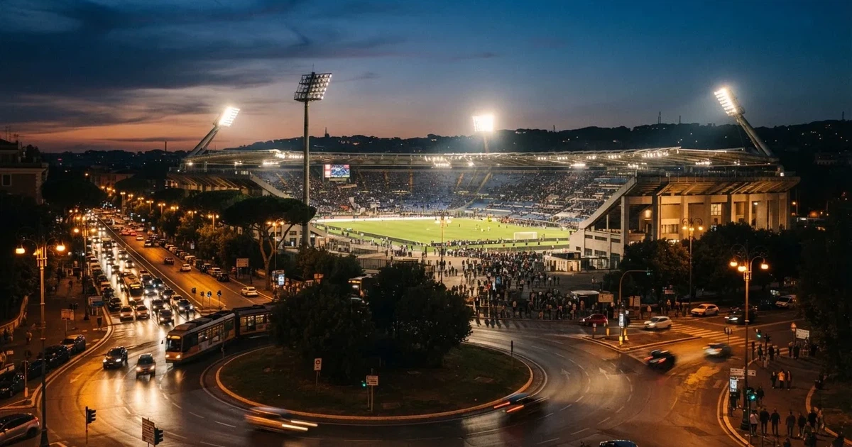 Ein Fußballstadion in der Dämmerung aus der Ferne, die Flutlichter gerade eingeschaltet, davor ein Kreisverkehr mit Laternen.